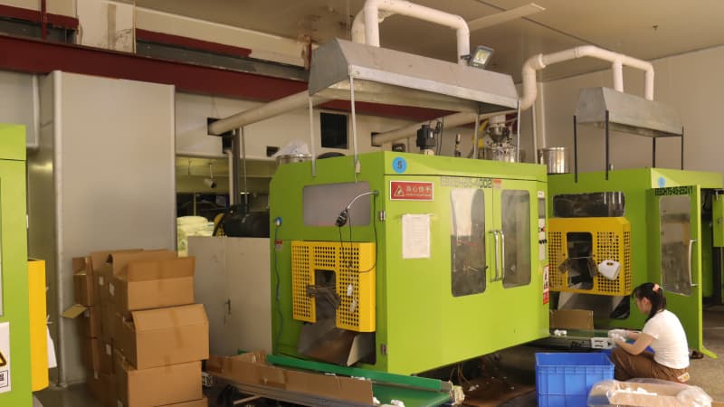 No.5 blow molding machine with exhaust system, worker inspecting finished bottles at the end of the conveyor line