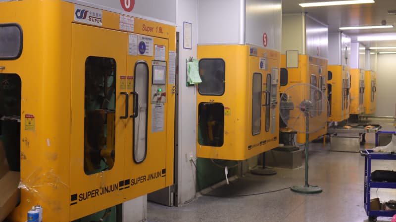 Row of yellow SUPER JINJUN blow molding machines with serial numbers, neatly arranged in a clean production workshop