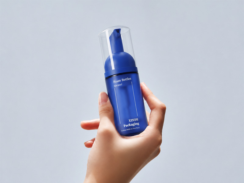 Matte blue 80ml plastic foam pump bottle held in hand, empty portable cosmetic skincare packaging