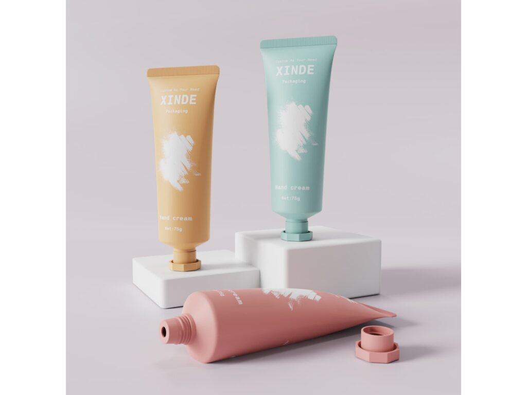 Three matte hand cream tubes in yellow, mint, and pink, 75g, one laid flat with cap removed